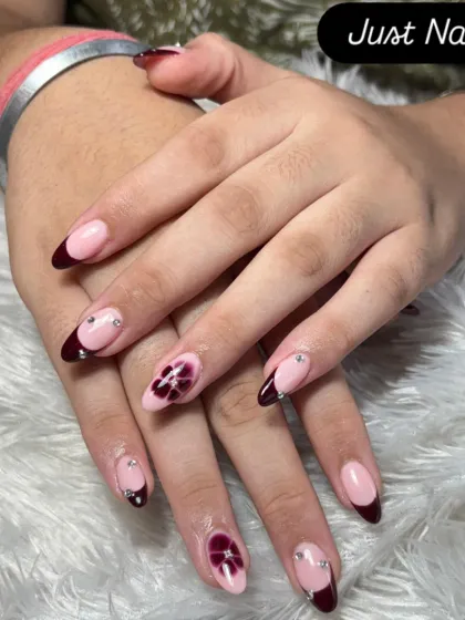 A sophisticated design with a deep burgundy v-shaped French tip, accented with hand-painted floral art and delicate rhinestones.