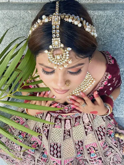 A detailed overhead view of a bridal look, focusing on the eye makeup and elaborate matha patti. This showcases the precision our students are trained to achieve.
