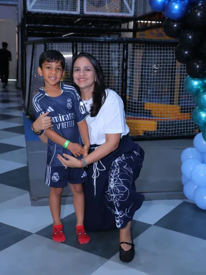 A mother and son, dressed in a football jersey, smile for the camera at a sports-themed party.