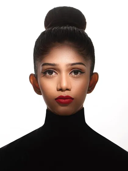 A powerful, clean headshot is essential for any model's portfolio. This image showcases a classic, high-fashion look with a tight bun, sharp cat-eye liner, and bold red lips. The high-key lighting ensures the focus remains entirely on the model's strong features and direct gaze.