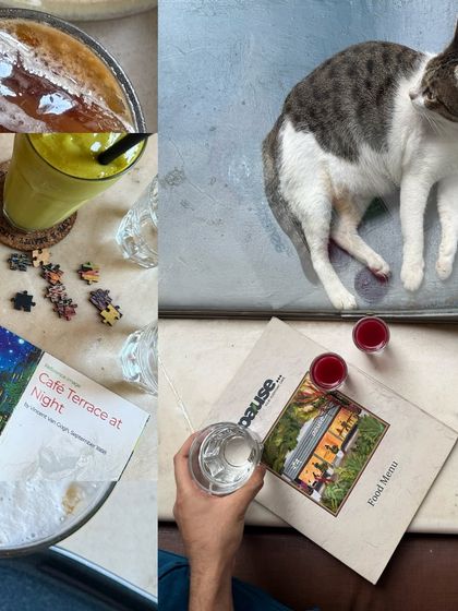 The details of a slow afternoon: a half-finished puzzle, a cat napping on a menu, and refreshing drinks.