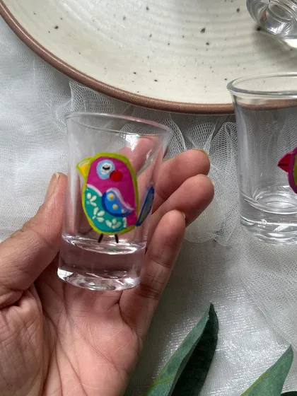 Holding one of the cute bird shot glasses to show its small size and detailed painting.
