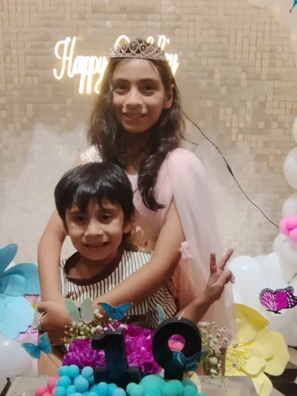 The birthday girl and her brother posing by the cake.
