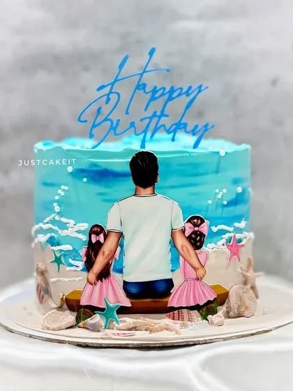 A heartwarming cake for a father who shares his birthday with his two twin daughters. The hand-painted design captures a beautiful family moment on the beach.