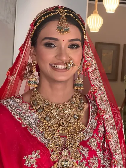 For this bride's traditional wedding ceremony, I created a sleek hair look with a center part to perfectly frame her matha patti. The style is designed to complement her magnificent jewelry and red bridal lehenga.