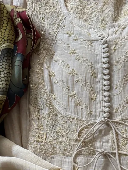 Our Achkan style Anarkali in Tissue Chanderi offers a structured yet fluid silhouette. The regal design is adorned with heavy Chikankari, further elevated with shimmering Kutdana, sequins, and Kasab work for a refined and timeless charm.