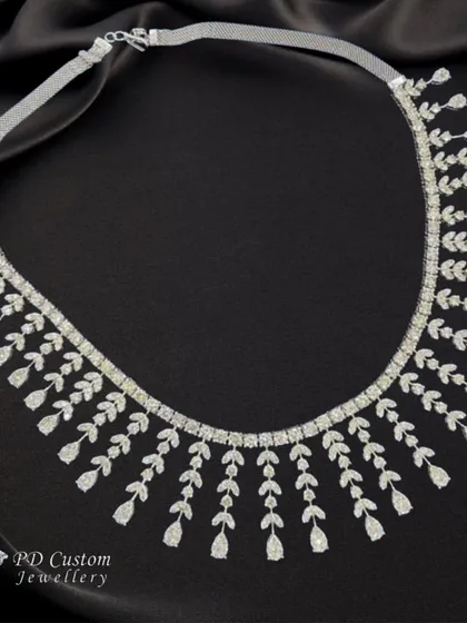 A stunning diamond necklace with a delicate, cascading leaf design. This piece is perfect for a reception or engagement party, offering a modern and sophisticated alternative to heavier traditional sets.