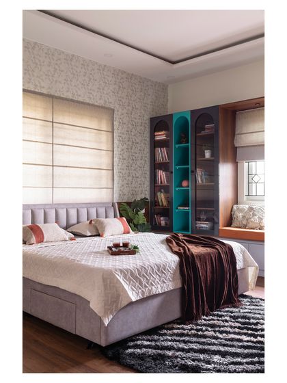 A wider view of the bedroom, showing the balance between comfort and style. The room includes a cozy window seat for reading and a custom bookshelf with a pop of teal for a touch of personality.