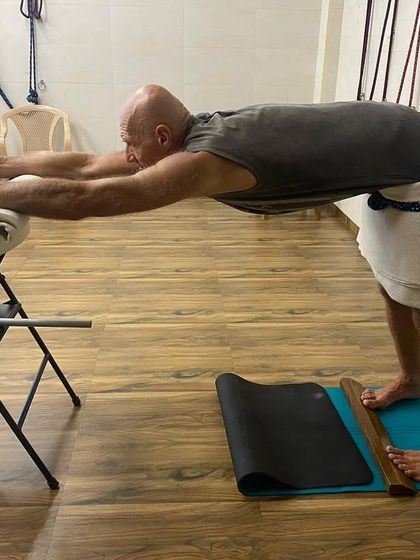 A student using a chair and wall ropes to create traction in the spine. This is an excellent way to lengthen the torso and relieve compression in the vertebrae.