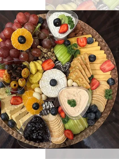 An overhead view of another one of our stunning cheese platters. We focus on creating a balanced and beautiful arrangement with a mix of hard and soft cheeses, fresh and dried fruits, and various crackers.