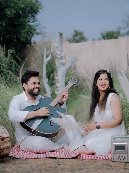 A joyful moment during the picnic-themed shoot. The groom-to-be plays the guitar while his partner sings along, creating a fun and interactive photo.