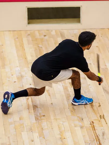 An image that demonstrates the incredible agility required for squash. This athlete is captured in a full lunge, showcasing the dynamic movement and flexibility I aim to freeze in my indoor sports photography.