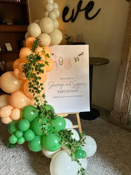 A warm welcome to the tropical baby shower, with a custom sign and a vibrant balloon garland adorned with jungle leaves.