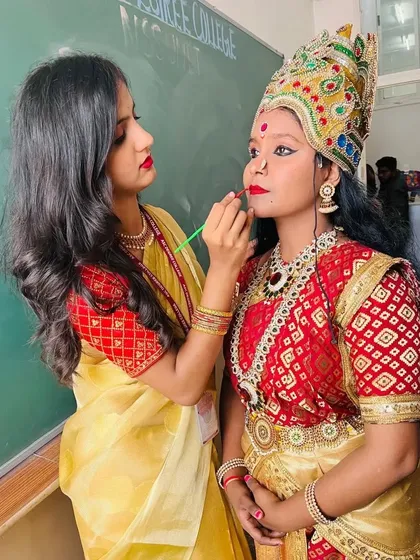 Adding the finishing touches for this traditional goddess look. Precise lip color and defined eyes are key for stage makeup, ensuring the performer's expressions are visible even from a distance.