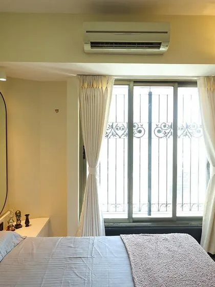 The serene bedroom retreat features a soft pink headboard, an arched wall panel, and an elegant oval mirror, creating a harmonious and stylish space.
