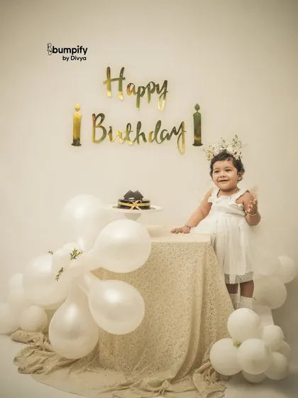 A happy smile from the birthday girl. She's so proud of her beautiful cake and the elegant white and gold setup for her milestone photoshoot.