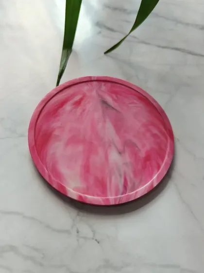 A close-up of our pink marble coaster. The vibrant swirls are created during the recycling process, ensuring no two coasters are ever exactly the same.