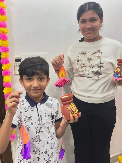 Siblings or friends proudly displaying the Diwali crafts they made together in our workshop.