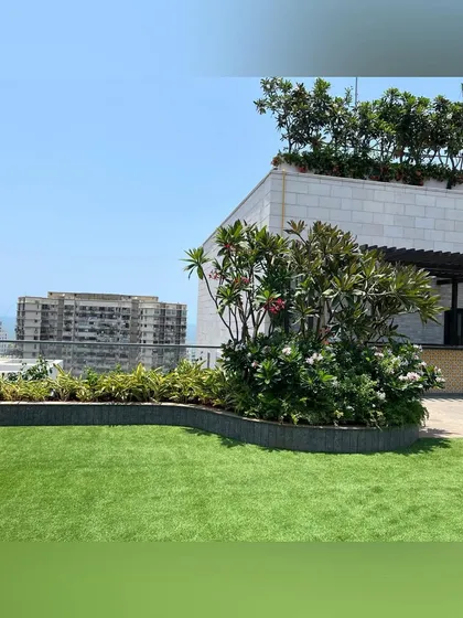Even on a rooftop, we can create the feeling of a real garden. This design features a rolling lawn bordered by curved planters filled with flowering shrubs and trees, softening the hard edges of the urban environment.