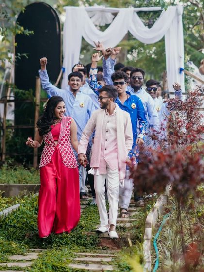 The couple leading their enthusiastic groomsmen in a fun procession at the Haldi event.