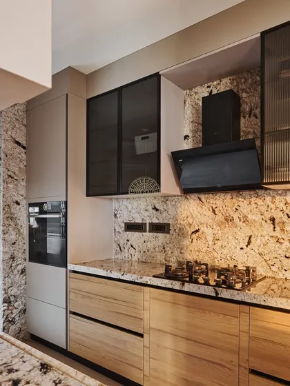 This kitchen in a Mumbai duplex features a striking granite with beautiful natural patterns on the countertops and backsplash. We paired it with wood-finish lower cabinets and frosted glass upper cabinets for a balanced look.