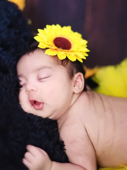 A sweet close-up of the newborn's face during the sunflower session, capturing a sleepy expression.