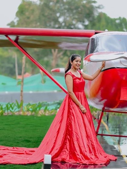 A solo portrait in a flowing red gown next to our red airplane, creating a glamorous and adventurous image.