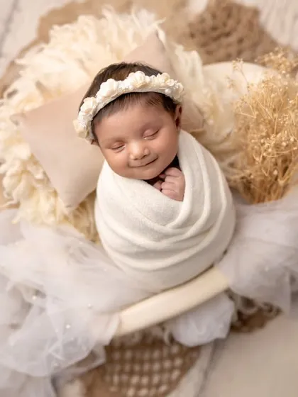 The pure, simple beauty of a newborn. This portrait captures a sweet, smiling newborn in a heart-shaped bowl, a symbol of all the love that surrounds them.