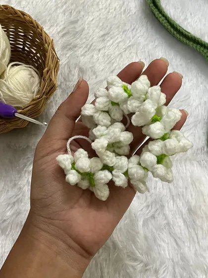 A close-up of the handmade jasmine gajra held in my hand. You can see the detail of the small white flowers with their green centers.