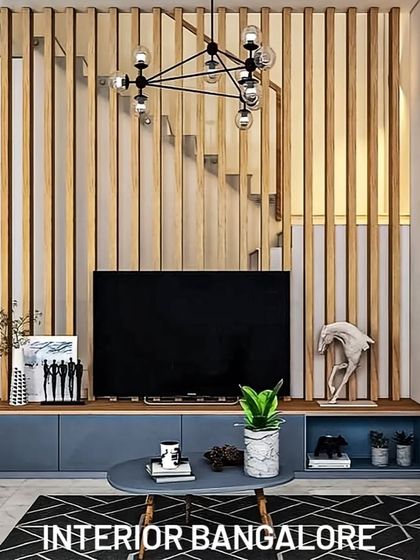 For this space, we used a vertical wooden slat partition as a dramatic backdrop for the TV unit. The low-profile blue console provides a touch of color and functional storage, creating a modern look that is perfect for open-concept homes.