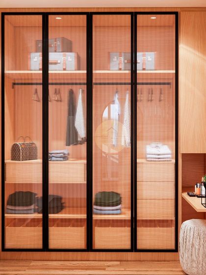 A close-up of the fluted glass wardrobe, showing the organized interior with space for luggage on top, a hanger rod, and multiple drawers and shelves for folded clothes and accessories.