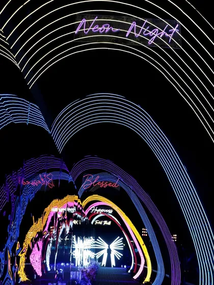 A tunnel of neon arches creates a futuristic and immersive entrance for guests, with words like 'Blessed' and 'Happiness' lighting the way into the 'Neon Night'.