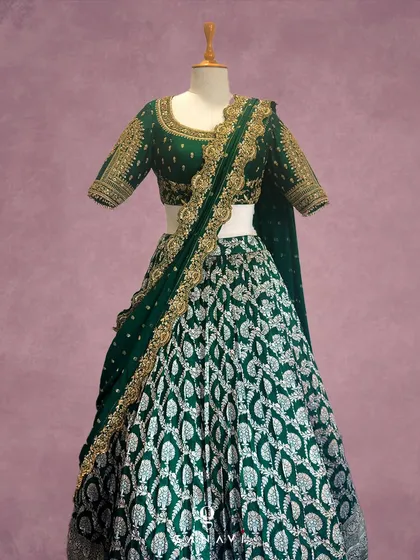 Inspired by the sacred architecture of South Indian temples, this emerald green lehenga is a work of art. The skirt features repeating motifs in silver and gold thread, while the blouse is adorned with detailed zardozi work, making it a regal choice for a wedding or grand reception.