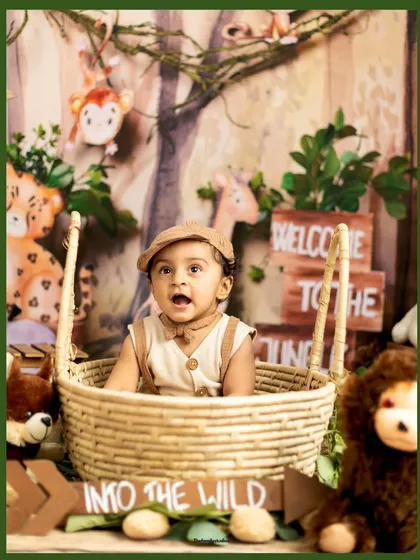 A baby boy peeking out of a basket in our jungle-themed set, looking like a true adventurer.