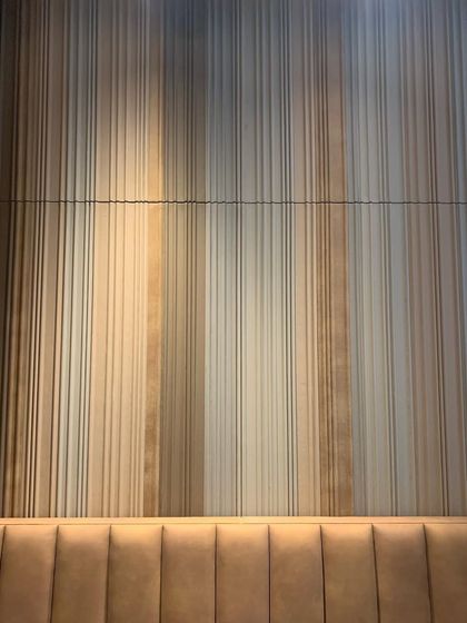 Texture can create incredible depth and movement. This feature wall is composed of fluted panels with subtle color variations, creating a curtain-like effect that is both visually soft and architecturally linear.