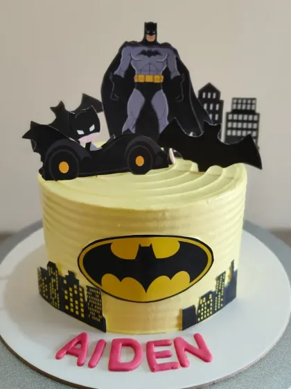 A Batman themed cake for a young superhero fan, featuring the iconic bat signal and Gotham city skyline.