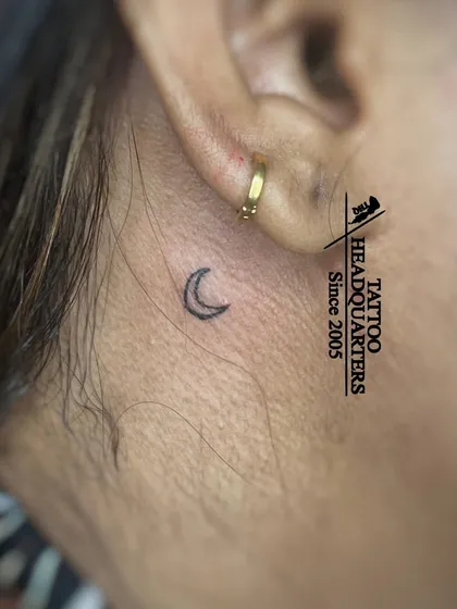 Another example of a tiny crescent moon tattoo behind the ear, a popular and subtle placement.