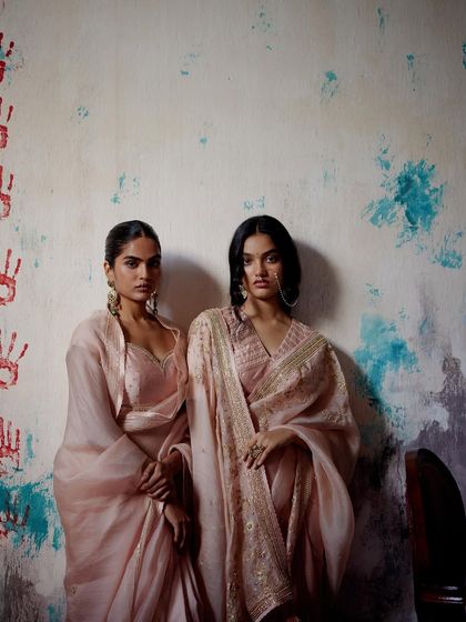 Another angle of the ethereal pastel pink sarees, highlighting the sheer fabrics and intricate gold work.