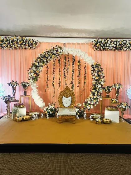 A wide shot of the stage, ready for the celebration. The lighting is positioned to highlight the floral decor and create a warm glow.