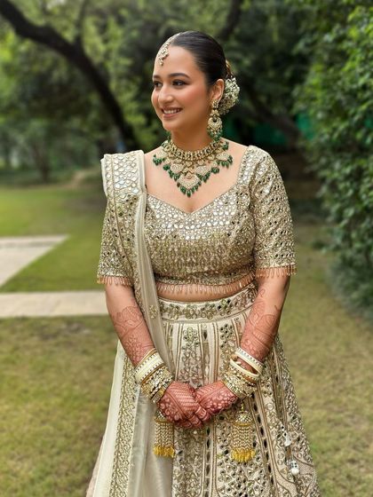 A dreamy look for a dreamy bride. Her ivory and gold lehenga was paired with a soft glam look, featuring a clean bun and emerald jewelry for a pop of color.