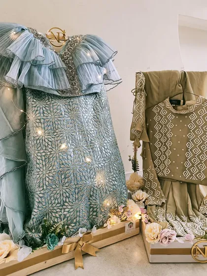 Your dream wedding trousseau, brought to life. We design stunning displays for your bridal outfits, like this pastel blue lehenga, using custom stands, delicate fairy lights, and floral arrangements for a truly magical presentation.