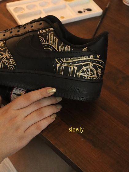 Slowly but surely, the design comes together. This shot shows the progress on the travel-themed black AF1s, with the city skyline and compass rose details taking shape.