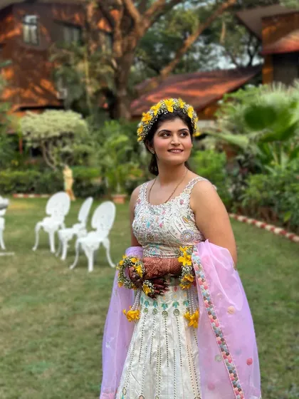 An outdoor shot of this beautiful Haldi look. The natural light highlights her glowing skin and the fresh, vibrant colors of her outfit and floral jewelry.
