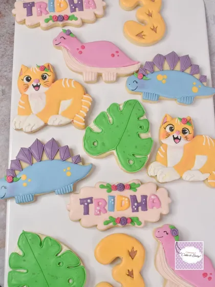 A set of dinosaur and cat-themed cookies to match a birthday cake. The birthday girl requested cats, so we happily added them to the dino party!