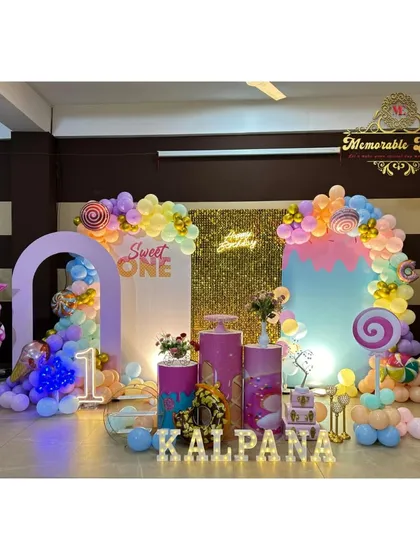 A sweet first birthday with our 'Candyland' theme, featuring large candy and ice cream props, a golden shimmer wall, and a colorful pastel balloon arrangement. This setup includes marquee letters and a neon sign for extra sparkle.