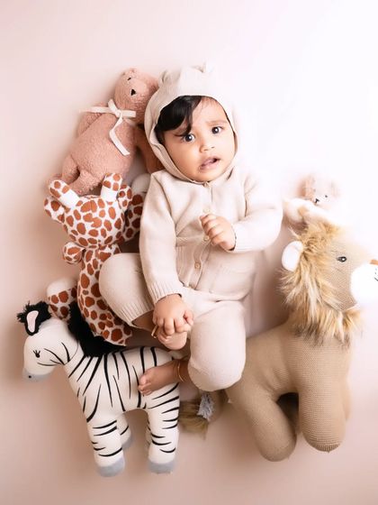 An overhead shot of this little one nestled amongst his safari animal friends. This creative angle provides a unique and adorable perspective for a baby photoshoot.