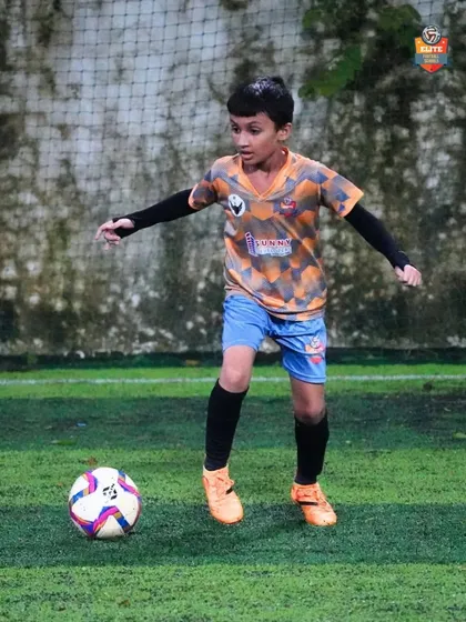 A young player practices his dribbling, keeping his head up to scan the field.
