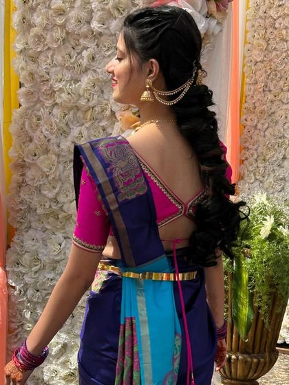 A side view of the client, showing her beautiful hairstyle and the vibrant color combination of her saree and blouse.