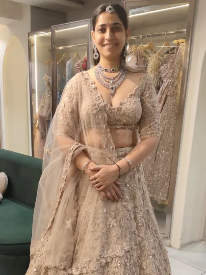 A happy client looking elegant in a beige lehenga paired with our sapphire and diamond look necklace set. A perfect choice for a reception or engagement.