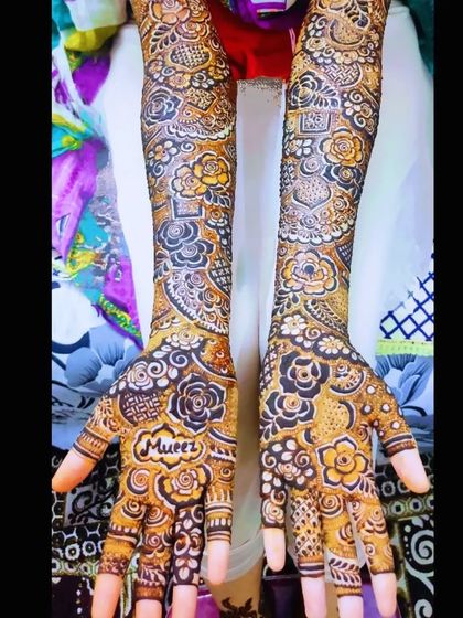 A full coverage bridal design with the name 'Mueez' on the palm.
